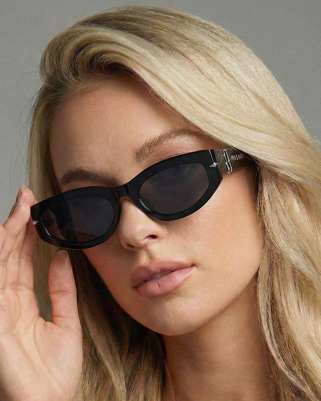 Woman wearing black sunglasses with a neutral background