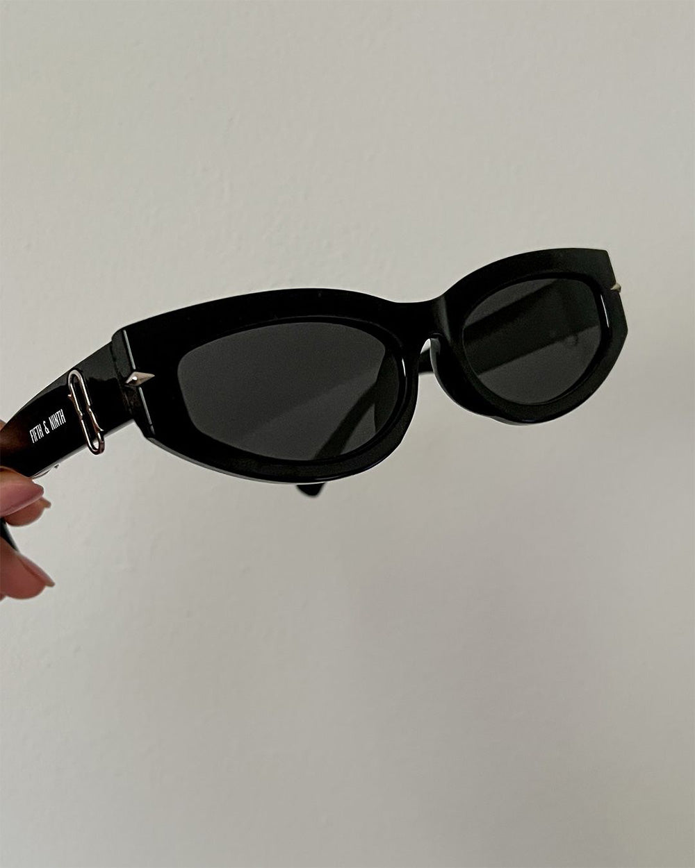 Black sunglasses held against a plain background