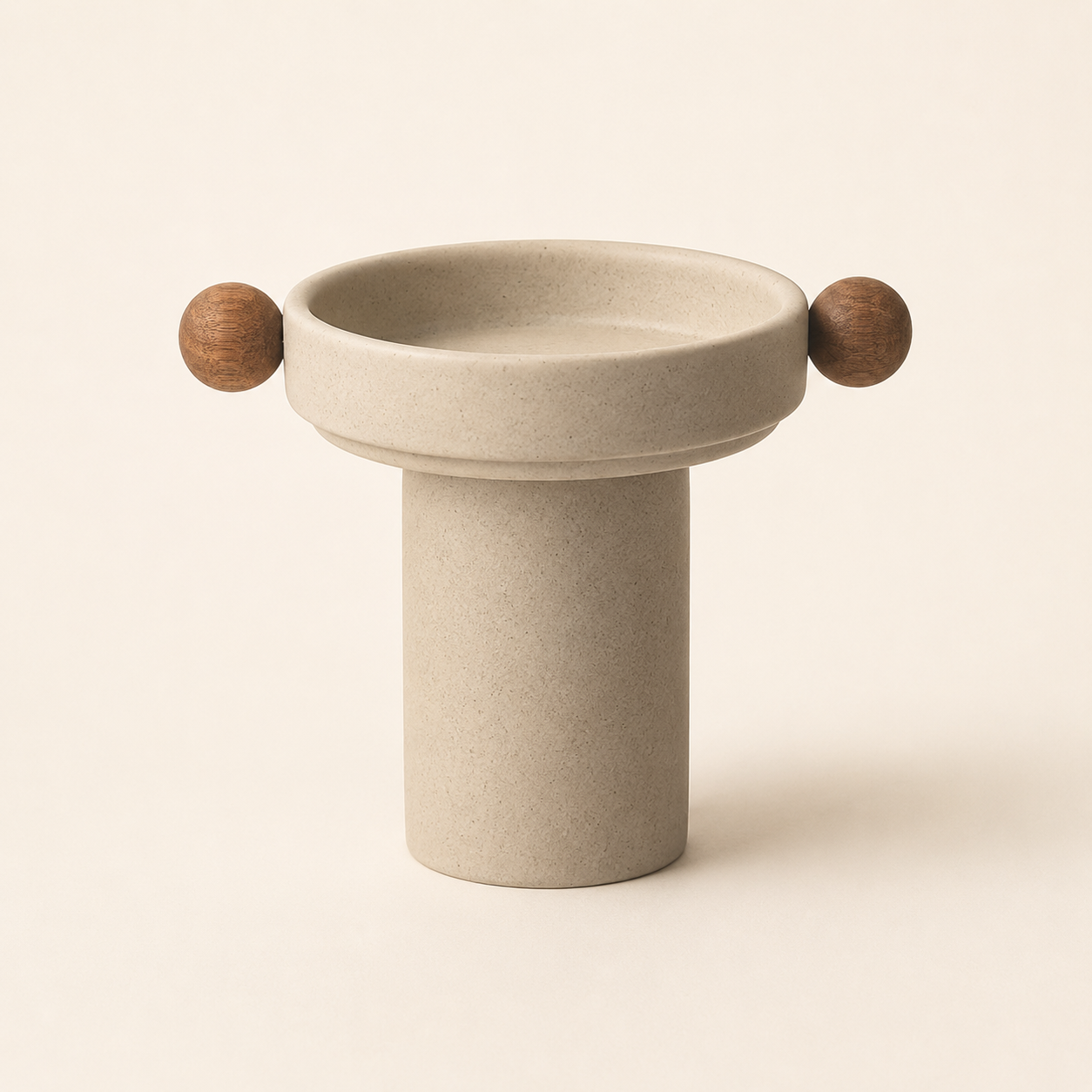 A minimalist ceramic pedestal planter with a wide, shallow round bowl and two small wooden sphere handles on either side, shown on a warm cream background.