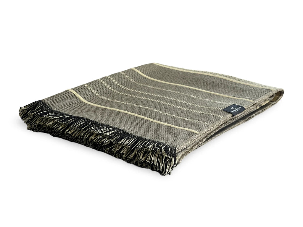 Folded green blanket with black fringe on a white background