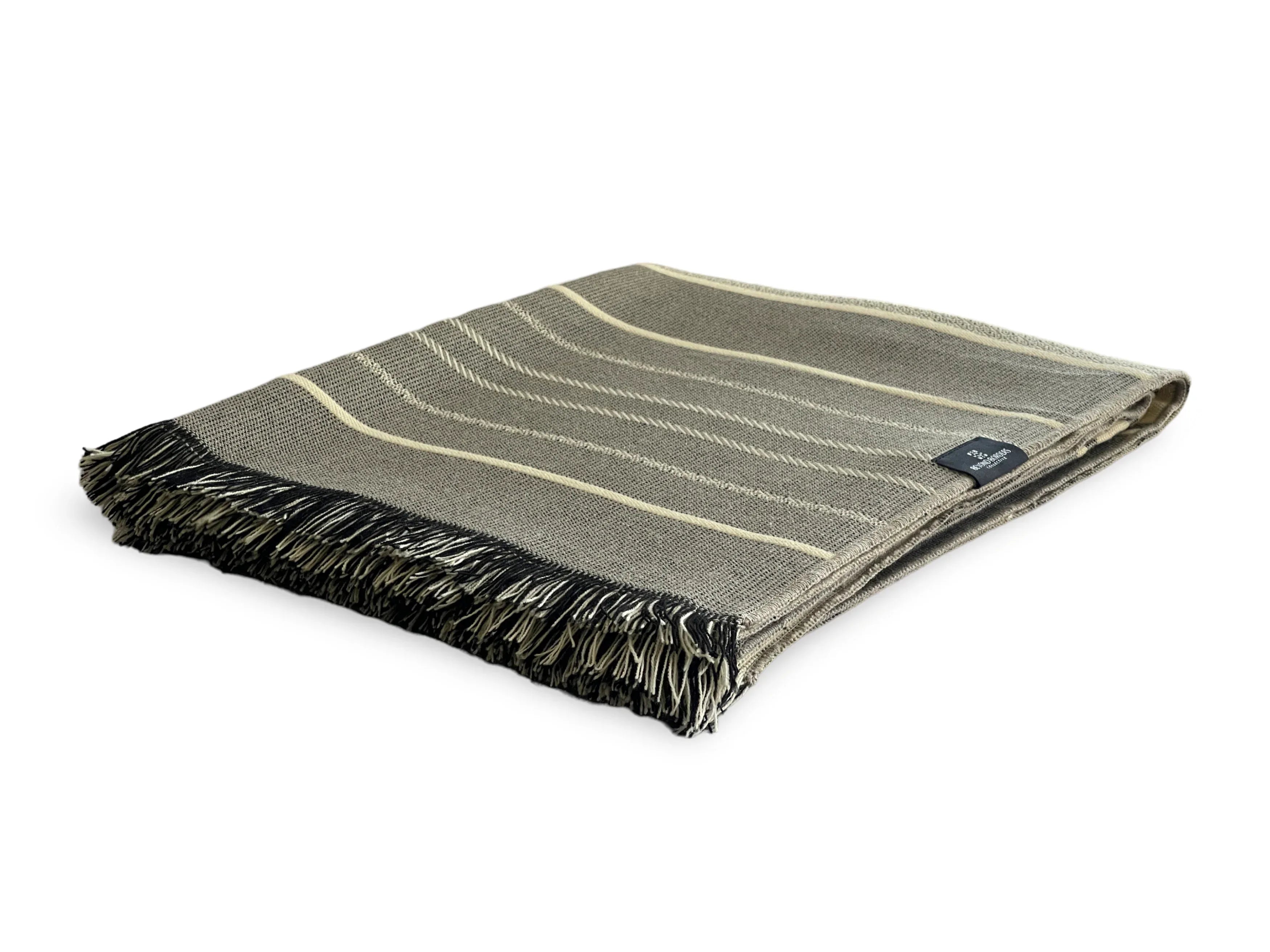 Folded green blanket with black fringe on a white background