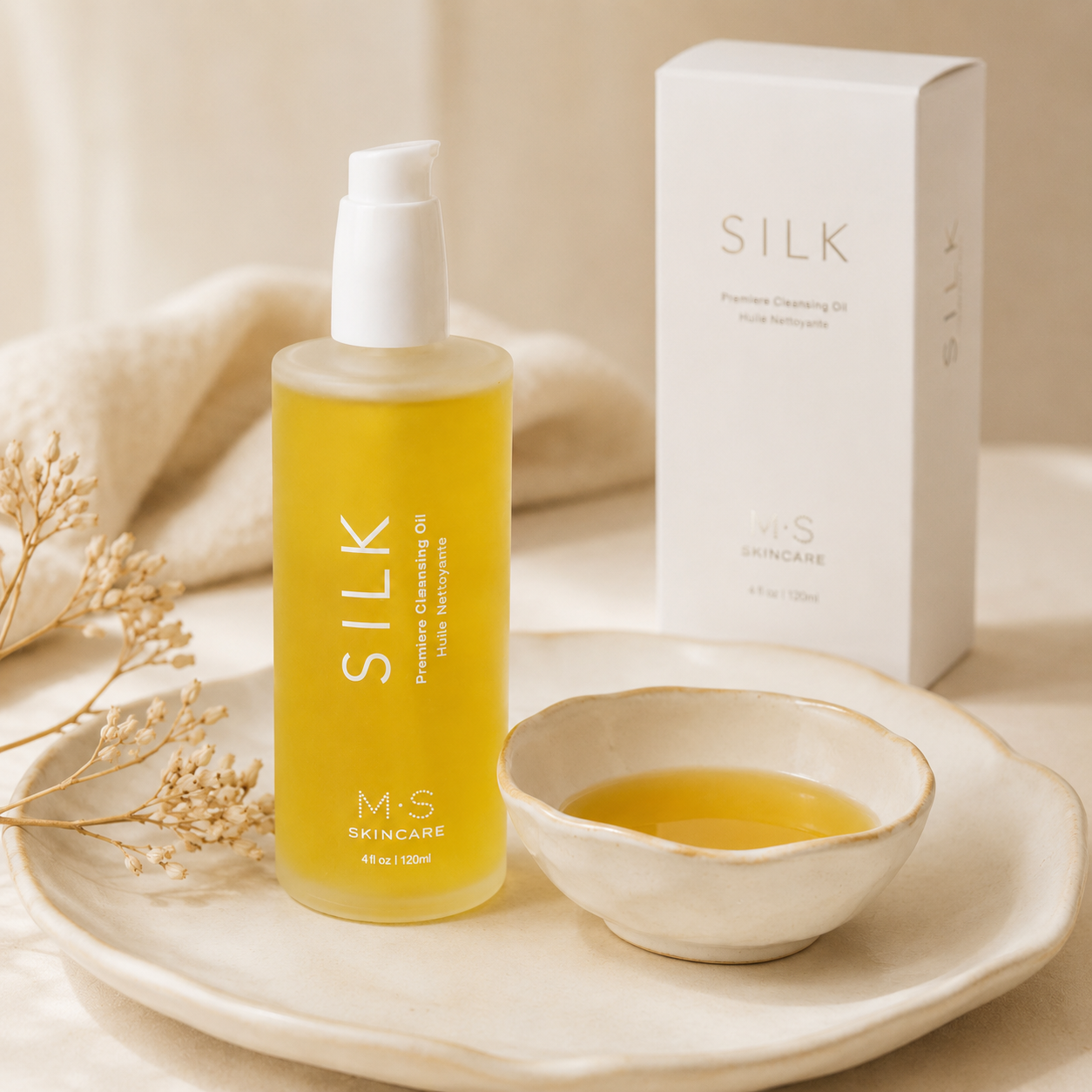 M.S Skincare Silk Pyrimidine Cleansing Oil in a frosted bottle with a white pump, displayed on a ceramic tray next to a small bowl of oil and its white packaging box.