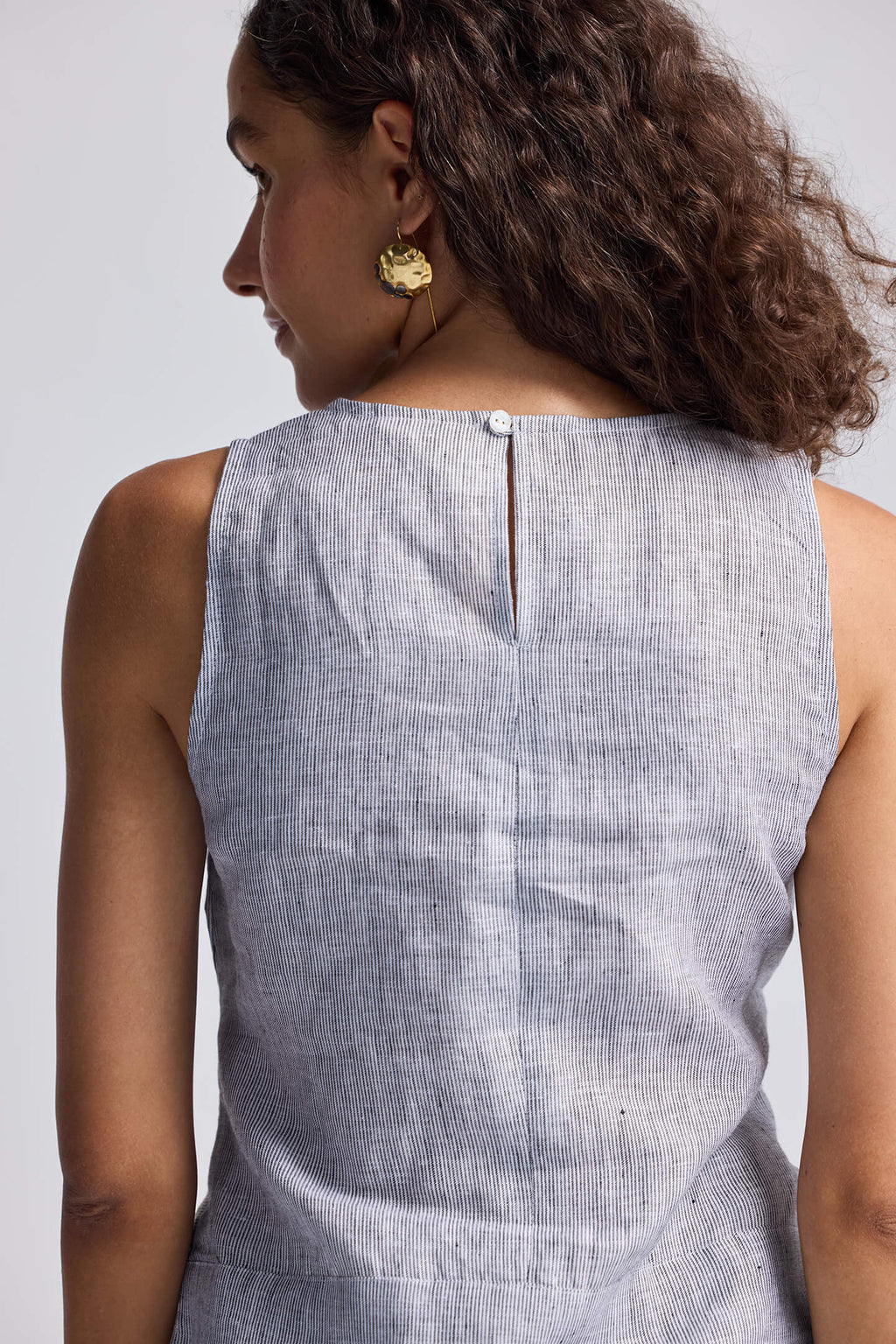 Woman wearing a sleeveless gray top against a plain background