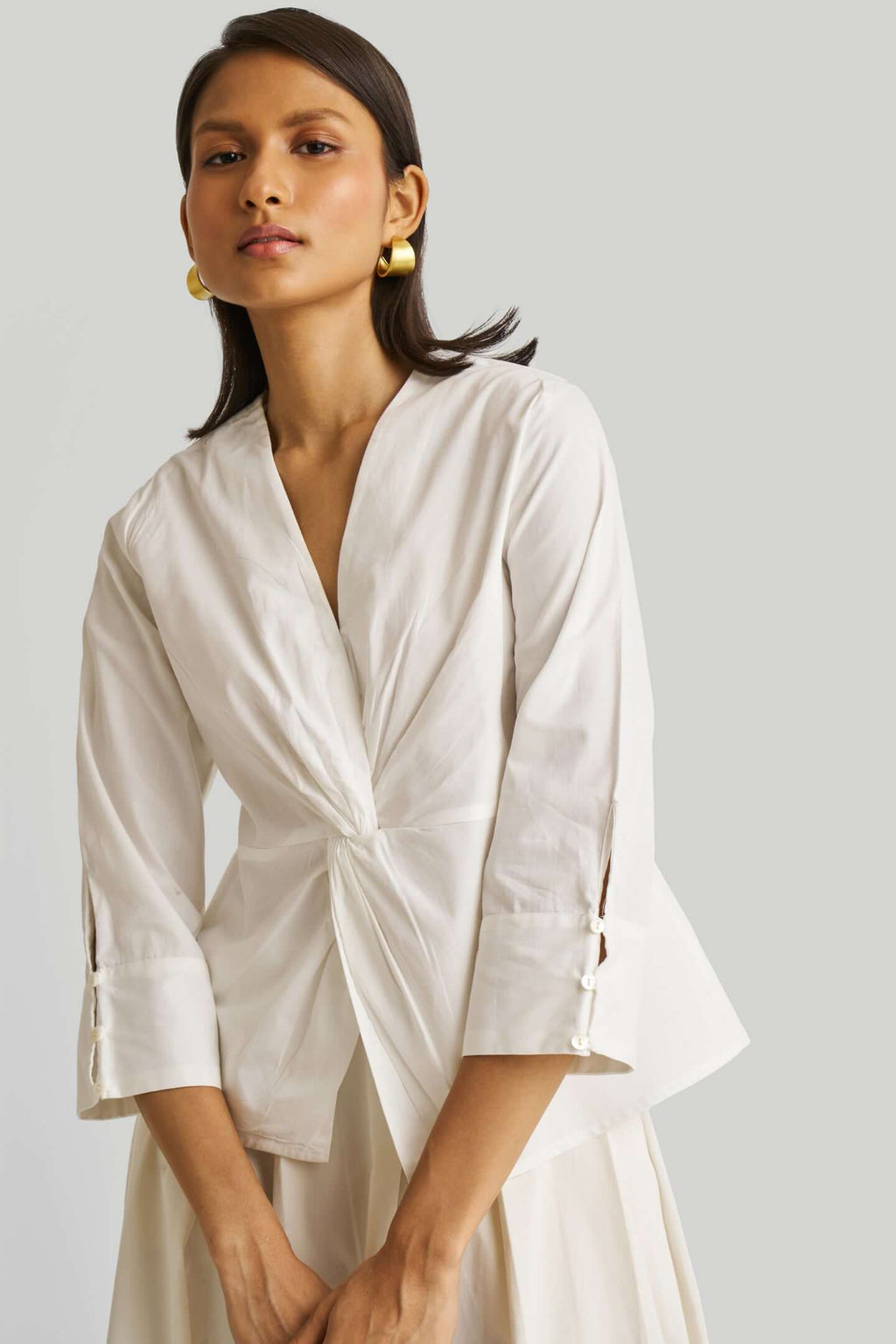 Woman wearing a white top with a plain background