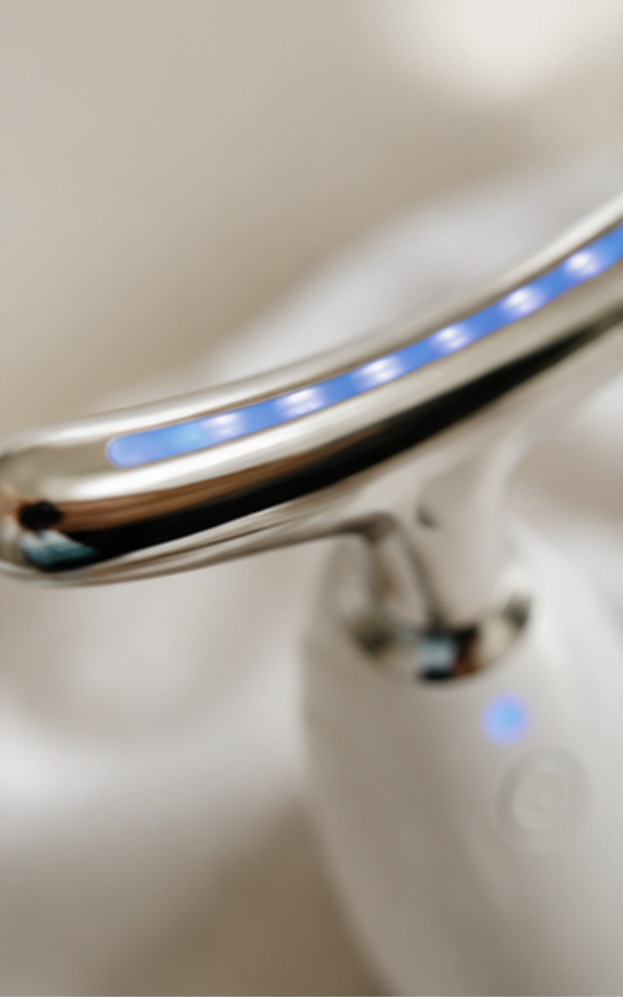 Close-up of a modern chrome faucet with a curved spout featuring a blue LED light strip, mounted on a white sink.