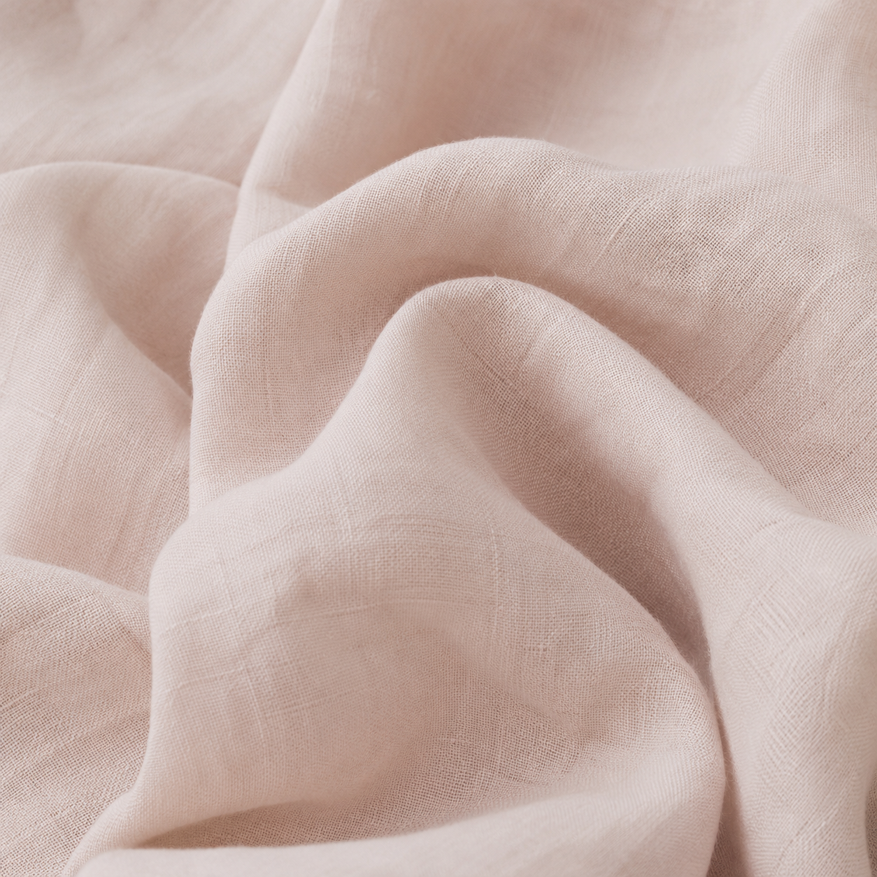A close-up of draped light blush pink fabric with a soft, textured weave.