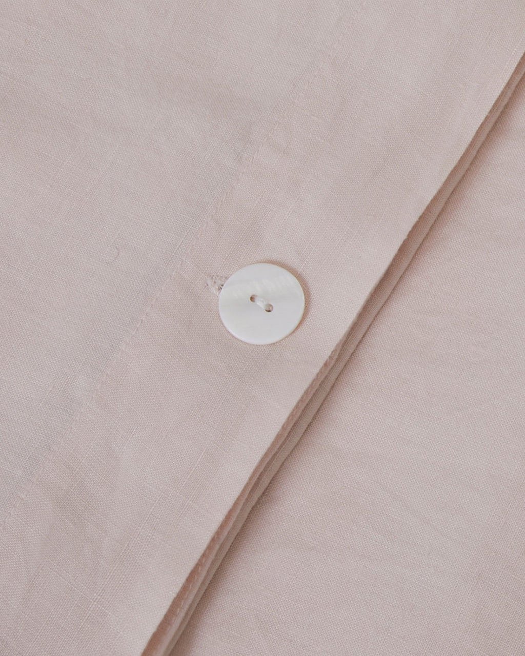 Close-up of a button on a light pink fabric
