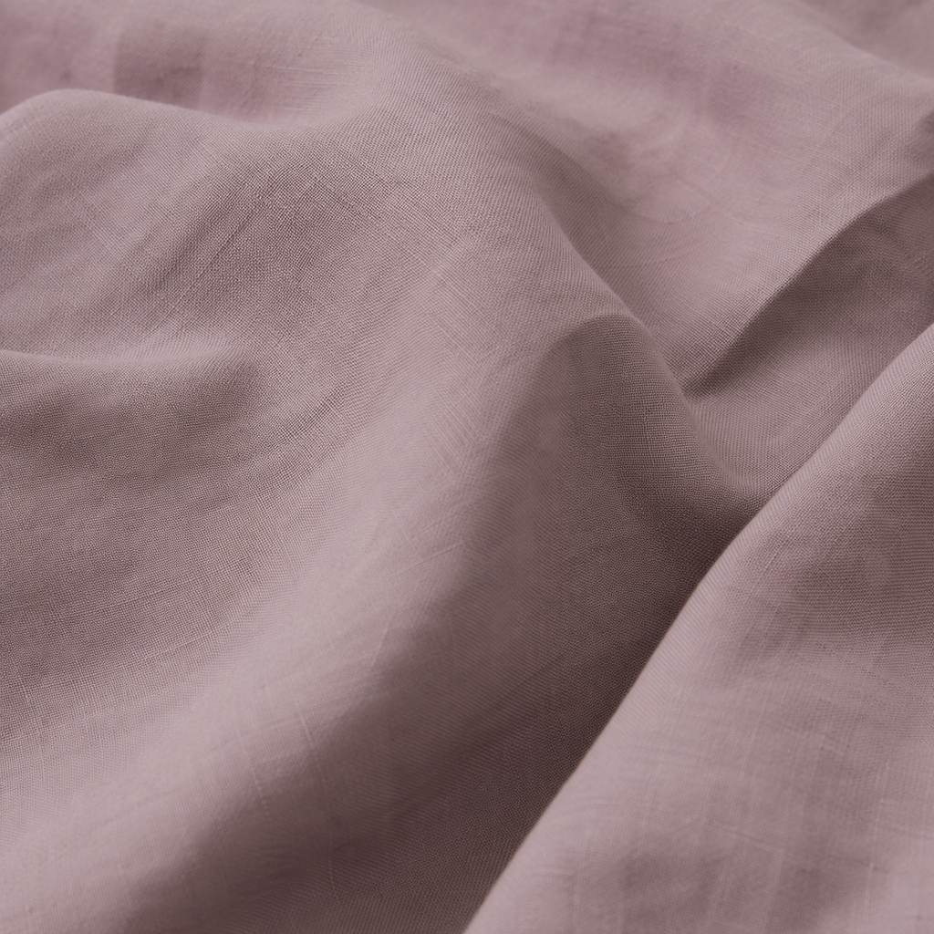 A close-up of draped dusty mauve fabric with a soft, textured weave and gentle folds.