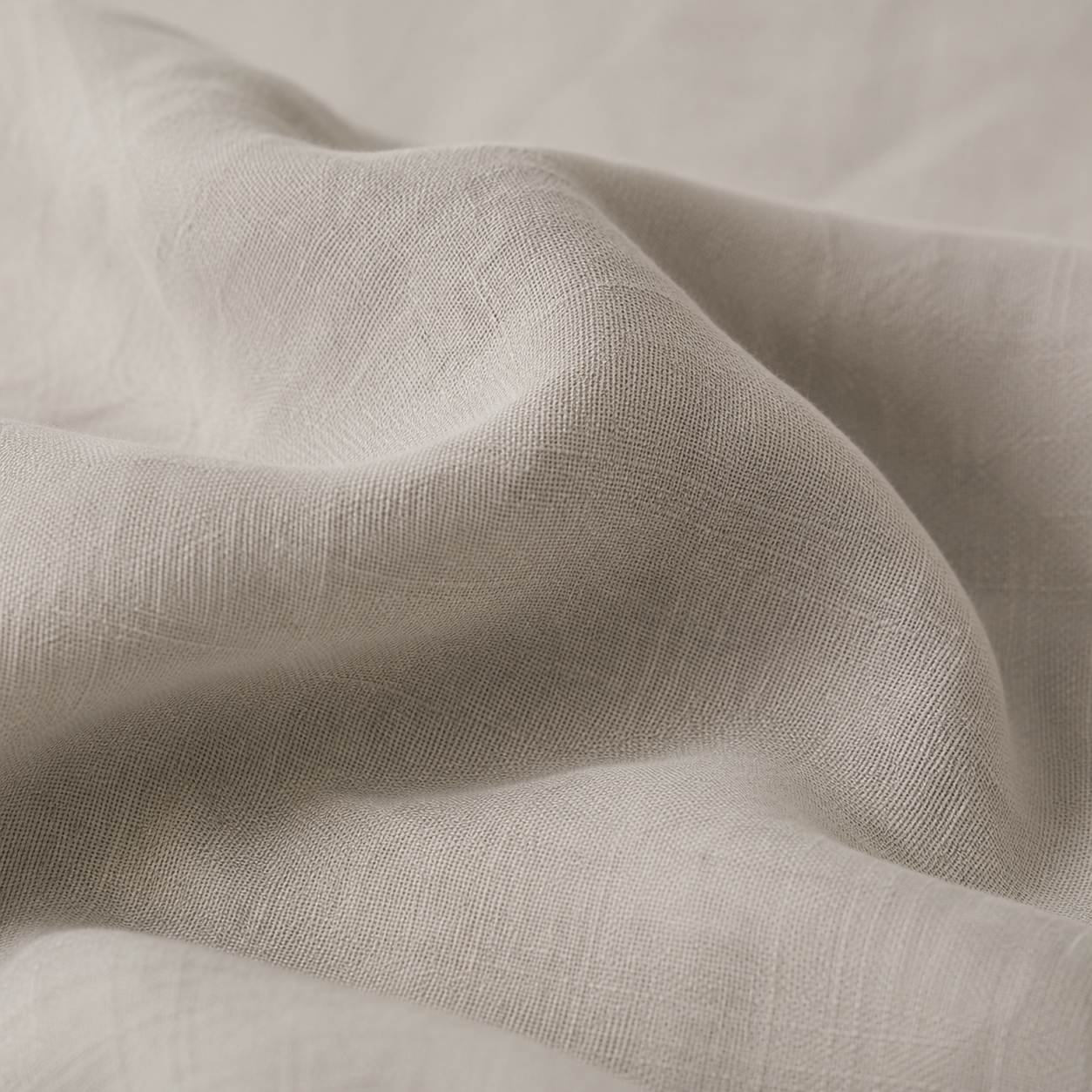 Close-up of draped light beige fabric with a soft, textured weave and gentle folds.