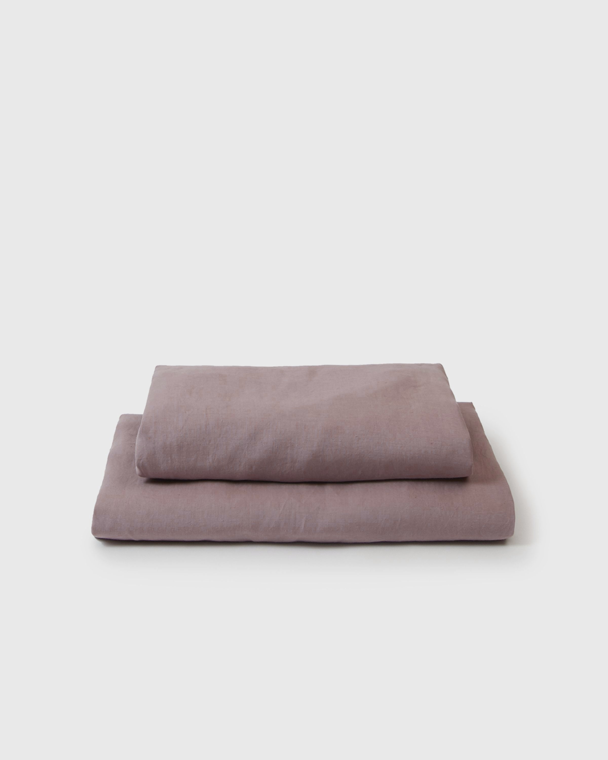 Folded purple bed sheets on a white background