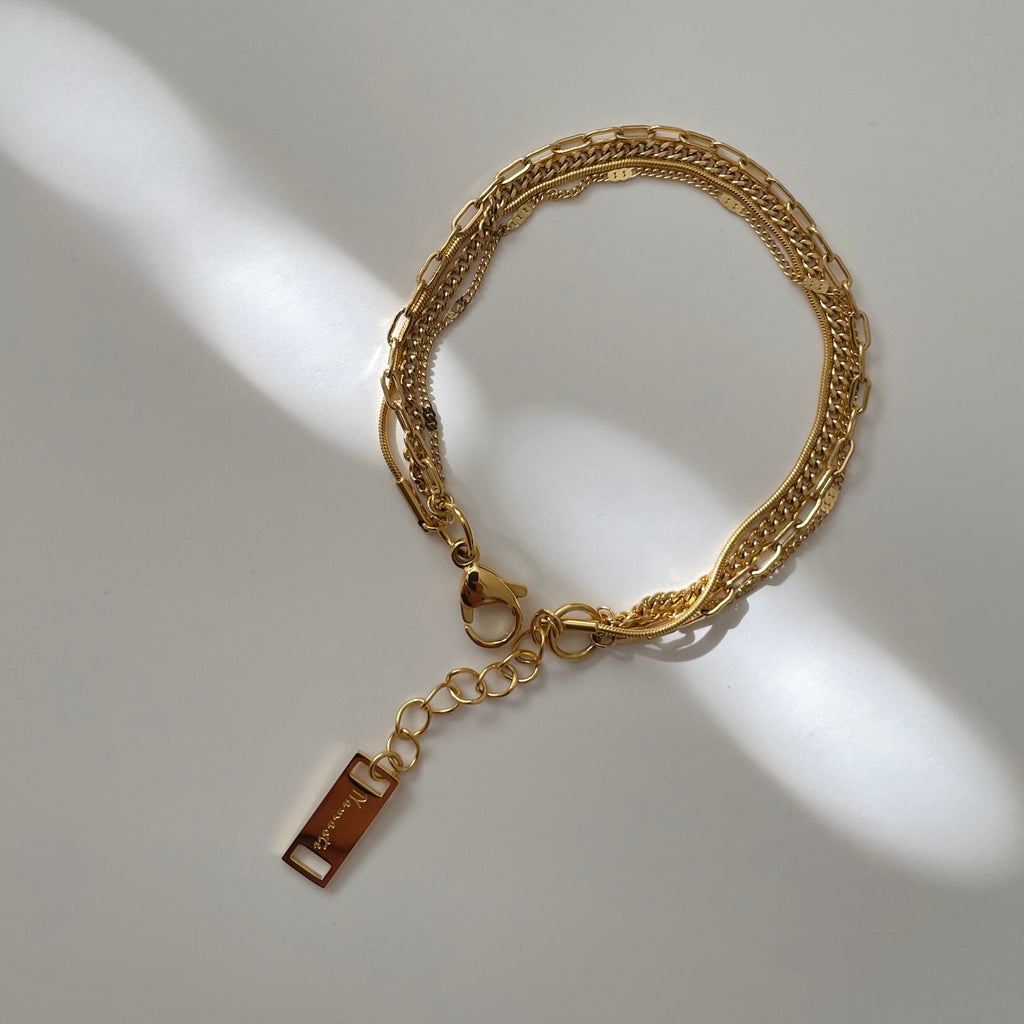 Gold chain bracelet with a tag on a light gray background