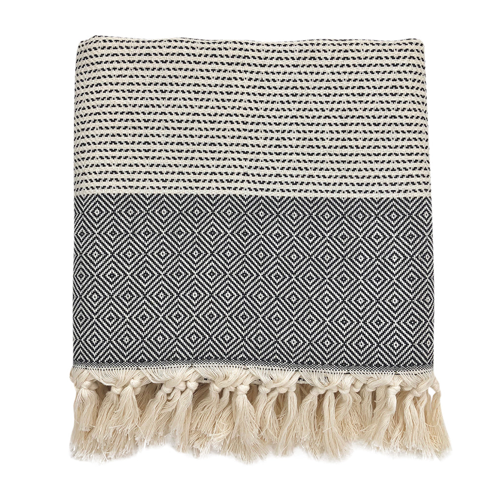 Black and white patterned towel with tassels on a white background